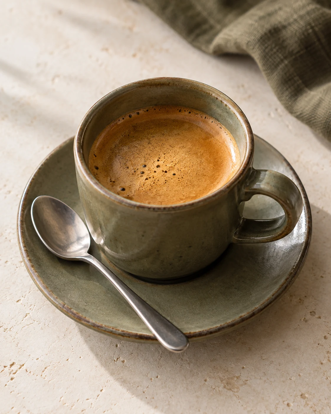 Fresh espresso in a ceramic cup on a sunlit table