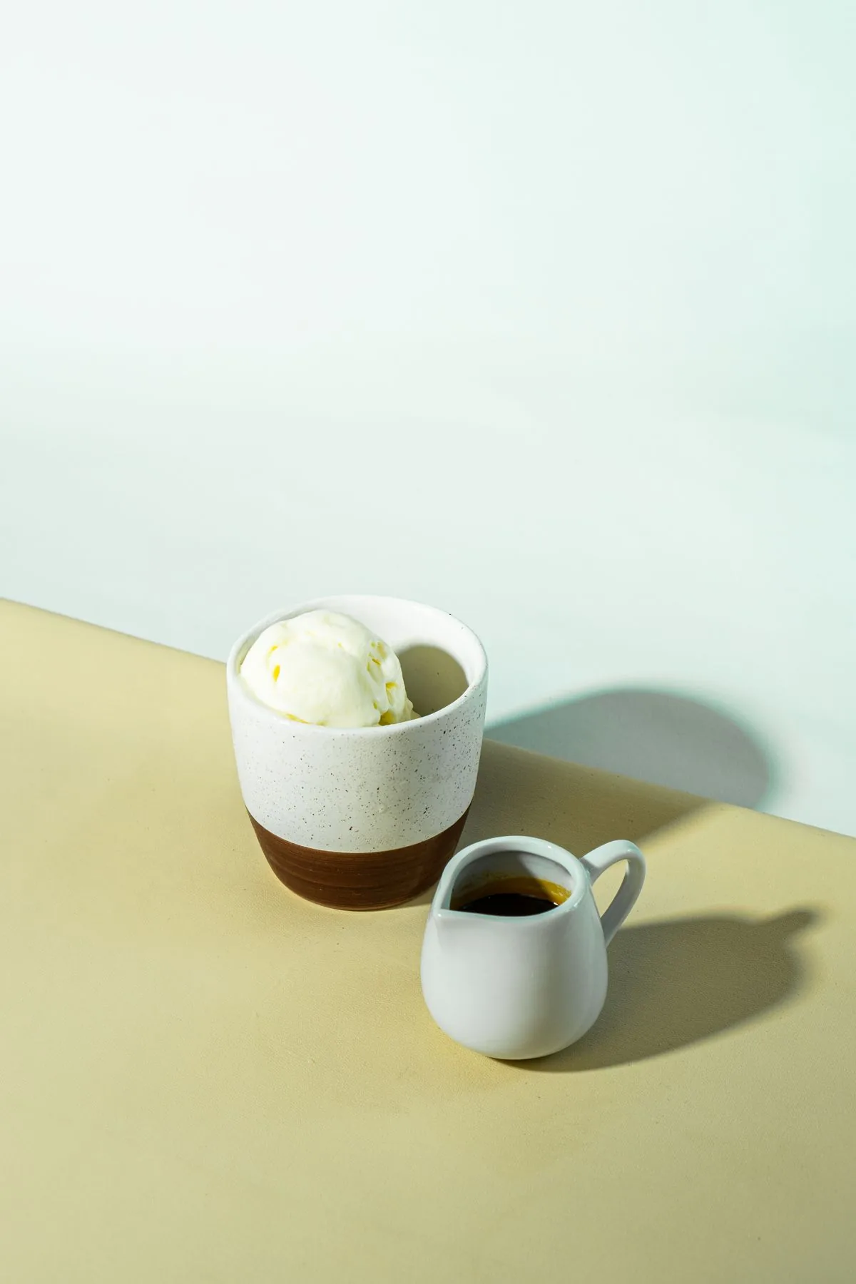 A scoop of gelato beside a small espresso pitcher